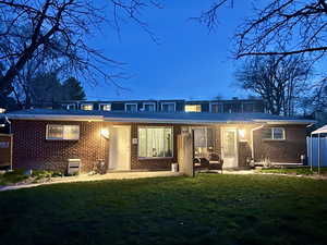 Front view of duplex at sunset with a lawn, divided front porches, and brick