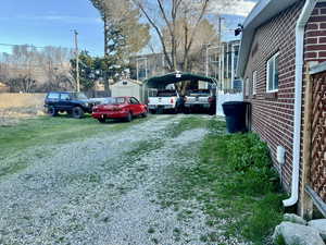 View of parking featuring covered parking, a detached carport, driveway, and a storage shed