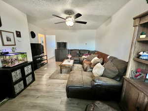 Unit 4365 Living room with light laminate floors, ceiling fan, and a textured ceiling