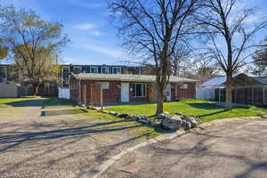 View of front facade featuring a carport, brick siding, driveway, and a storage shed