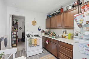 Kitchen featuring white appliances, light countertops, light wood-style floors, backsplash, and wood finish cabinets