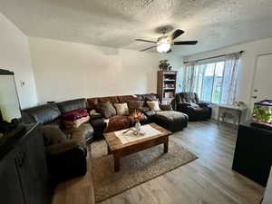 Unit 4365 Living area with laminate floors, a textured ceiling, and ceiling fan