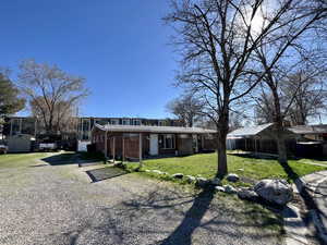 View of front of home featuring a detached carport, brick siding, a front yard, and driveway