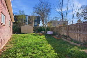 Fenced backyard with a vegetable garden and a storage unit