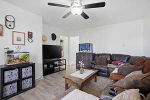 Living area featuring light wood-style flooring, a textured ceiling, and ceiling fan