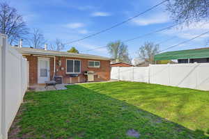 Back of property with a fenced backyard, a patio, and brick siding