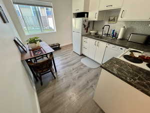 Unit 4365 Kitchen featuring dark countertops, light laminate floors, white cabinets, and white appliances including dishwasher