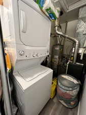 Unit 4367 Laundry area with stacked washer and clothes dryer, water heater, heating unit, and laminate flooring