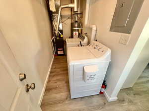 Unit 4365 Laundry room with electric panel, independent washer and dryer, water heater, and light laminate flooring