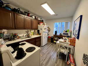 Unit 4367 Kitchen featuring white appliances, light countertops, dark wood finish cabinets, light laminate floors, and tasteful backsplash