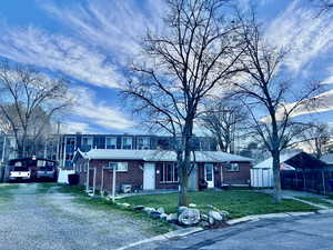 View of front facade duplex with brick, lawn, porches, covered parking, a carport, and driveways