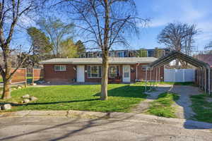 View of front facade featuring a carport, brick siding, and driveway