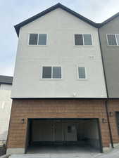 Back of property with a garage, stucco siding, and concrete driveway