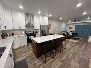 Kitchen featuring open floor plan, stainless steel appliances, a ceiling fan, a kitchen island, and a breakfast bar