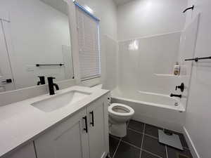 Full bath featuring vanity, bathtub / shower combination, and dark tile patterned floors