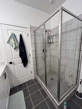 Full bathroom with a shower stall, dark tile patterned floors, and vanity