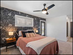 Primary suite featuring light carpet, a ceiling fan, designer walls, and a textured ceiling