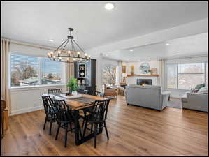 Dining space featuring a glass covered fireplace LVP flooring, hanging lights, and a textured ceiling