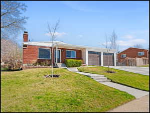 View of front of home featuring a chimney, an attached garage, driveway, and brick siding