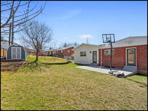 Rear view of house featuring entry steps, brick siding, and a shed
