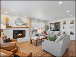 Living room with a glass covered fireplace, wood-like LVP floors, recessed lighting, and a textured ceiling