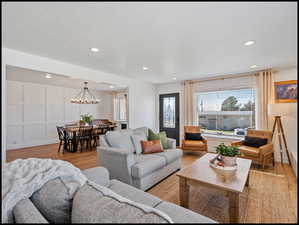 Living room with light LVP flooring, a decorative wall, and a chandelier