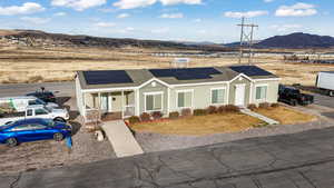 View of front of house featuring a shingled roof, solar panels, a porch, a mountain view, and a front yard