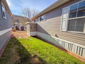 View of side of home featuring a storage shed and a lawn