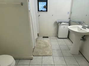 Full bathroom with light tile patterned floors and curtained shower