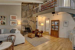 Living area with a high ceiling, light wood-style flooring, and a fireplace