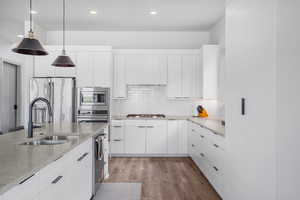 Kitchen with light wood-style flooring, stainless steel appliances, and white cabinetry