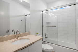 Full bathroom featuring vanity and bath / shower combo with glass door