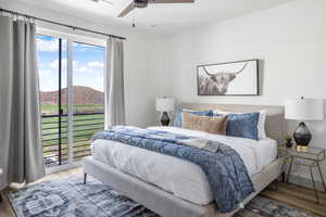 Bedroom featuring a mountain view, access to exterior, wood finished floors, and a ceiling fan