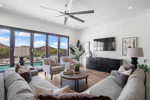 Living room with a ceiling fan, light wood-style flooring, and recessed lighting