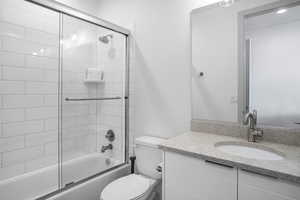 Full bathroom with vanity and bath / shower combo with glass door