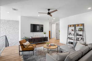 Living area featuring light wood finished floors, a ceiling fan, and recessed lighting