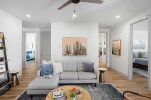 Living room with light wood finished floors, ceiling fan, and recessed lighting