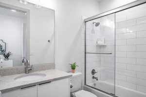Full bath with vanity and bath / shower combo with glass door