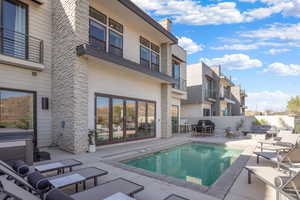 View of pool featuring patio surround, a balcony, a hot tub, and outdoor lounge area