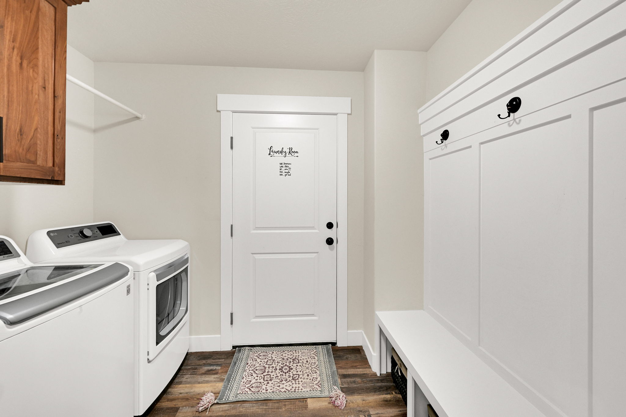 Laundry room with dark wood-style floors, washer and clothes dryer, and cabinet space