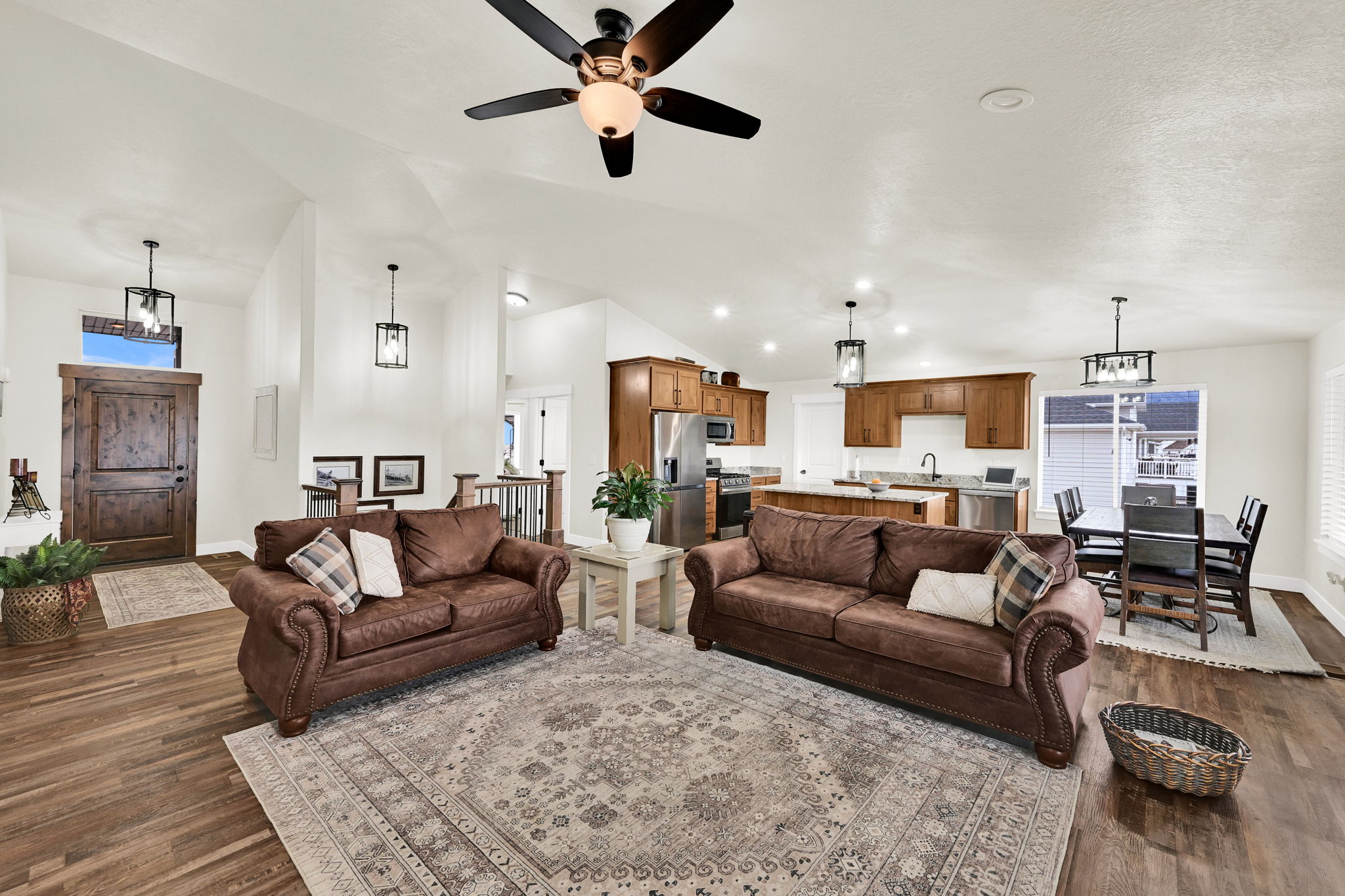 Living area featuring dark wood finished floors, lofted ceiling, ceiling fan, plenty of natural light, and hanging lights