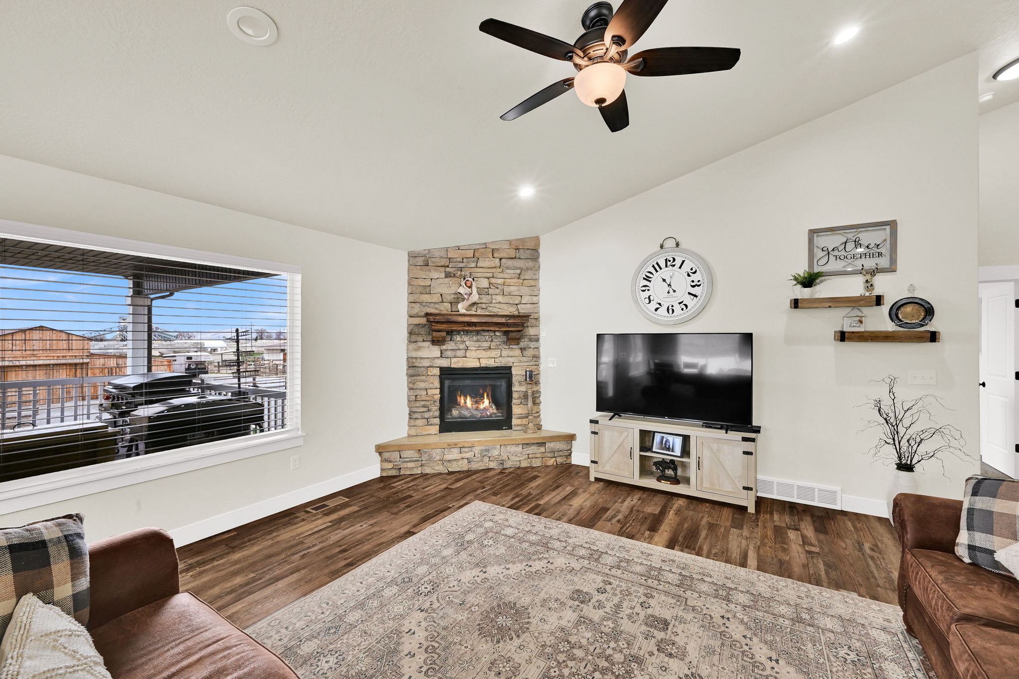 Living area with vaulted ceiling, dark wood-style floors, a ceiling fan, a fireplace, and recessed lighting