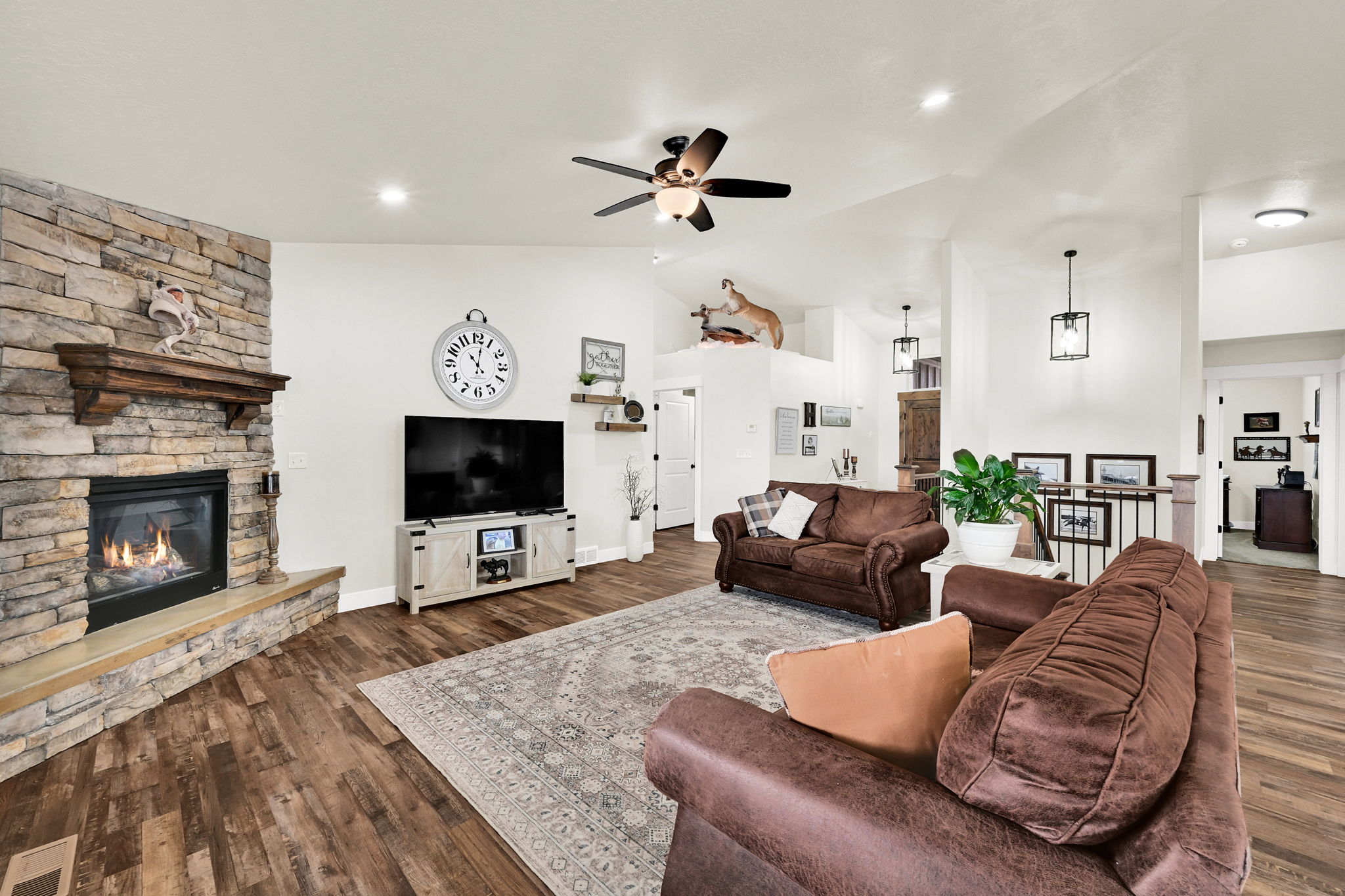 Living area featuring ceiling fan, a stone fireplace, dark wood-style floors, lofted ceiling, and recessed lighting