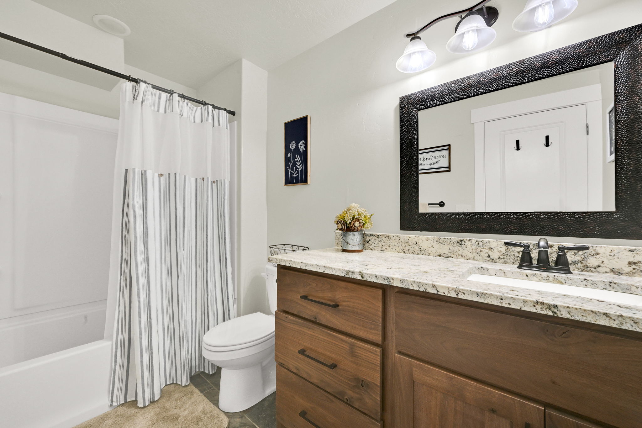 Bathroom with vanity, shower / bathtub combination with curtain, and dark tile patterned floors