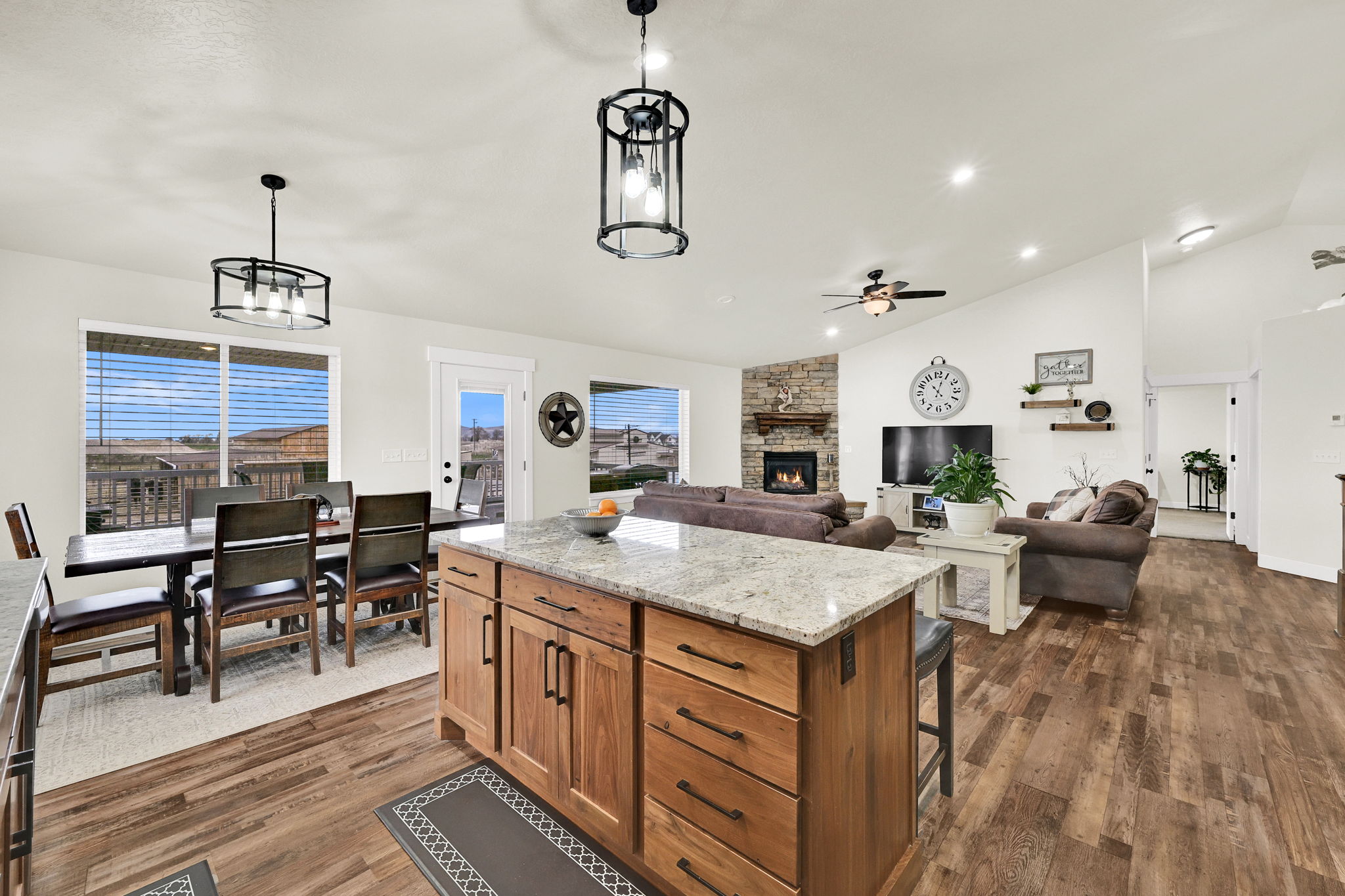 Kitchen featuring light stone counters, lofted ceiling, a kitchen island, dark wood-style floors, and open floor plan