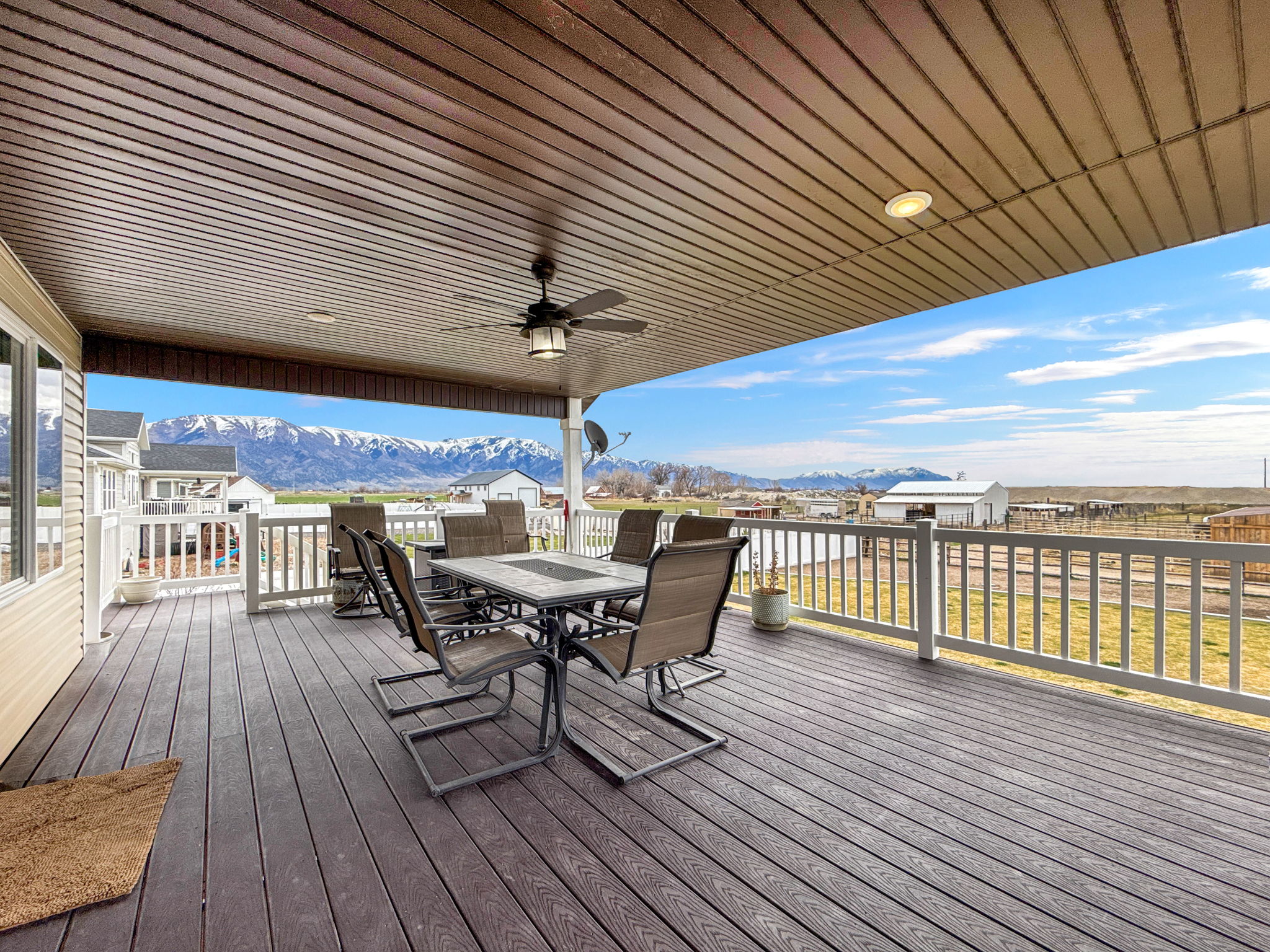 Wooden terrace featuring outdoor dining area, a mountain view, a ceiling fan, and a residential view