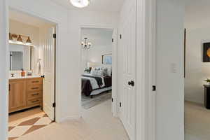 Corridor with suspended lighting, light colored carpet, and light floors