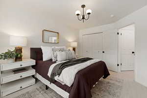 Bedroom featuring light colored carpet, a closet, and suspended lighting