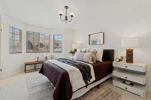 Bedroom featuring light colored carpet and hanging lights