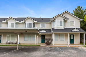 View of front facade with covered porch, a shingled roof, and uncovered parking